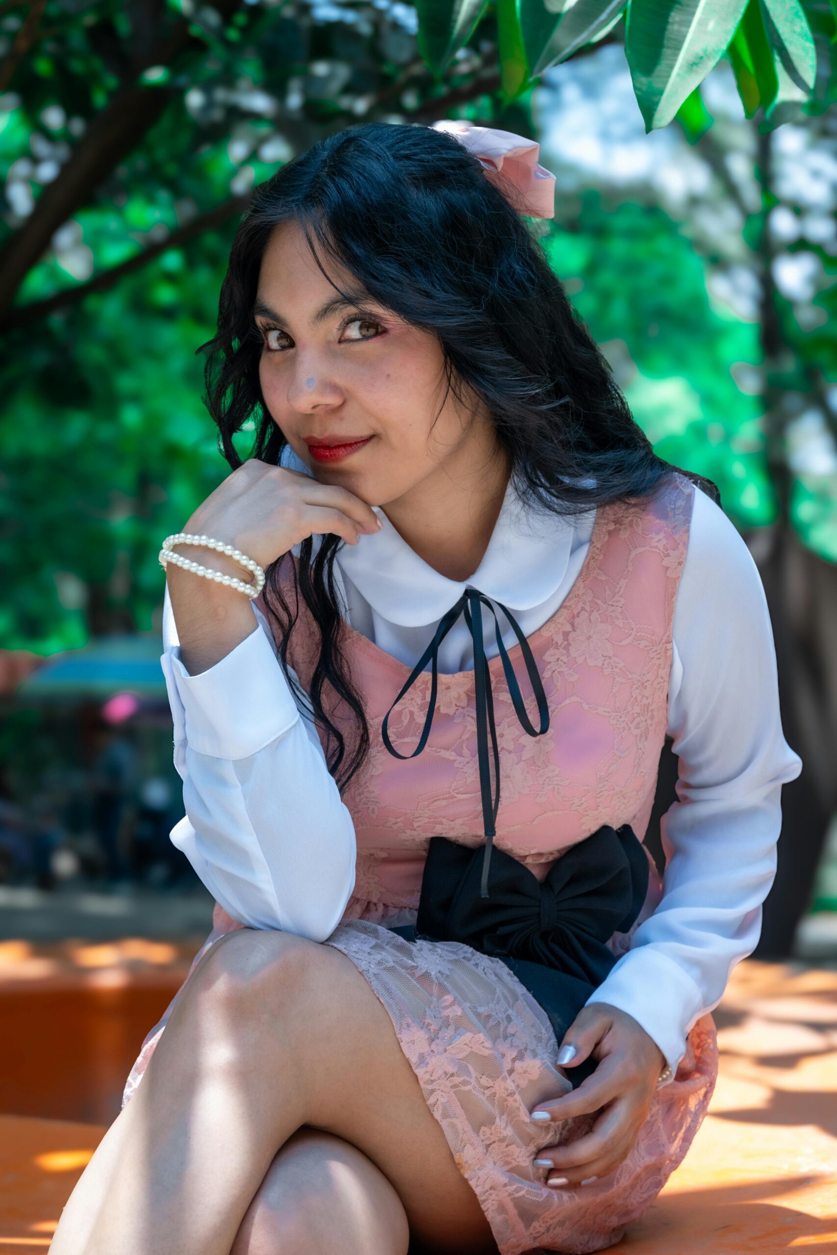 Elegant woman in pink dress poses outdoors in a Mexico City park, blending modern and classic styles.